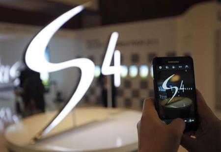 A man takes a photograph of a logo of Samsung Electronics Co Ltd's latest flagship smartphone S4 during its launch event in Seoul