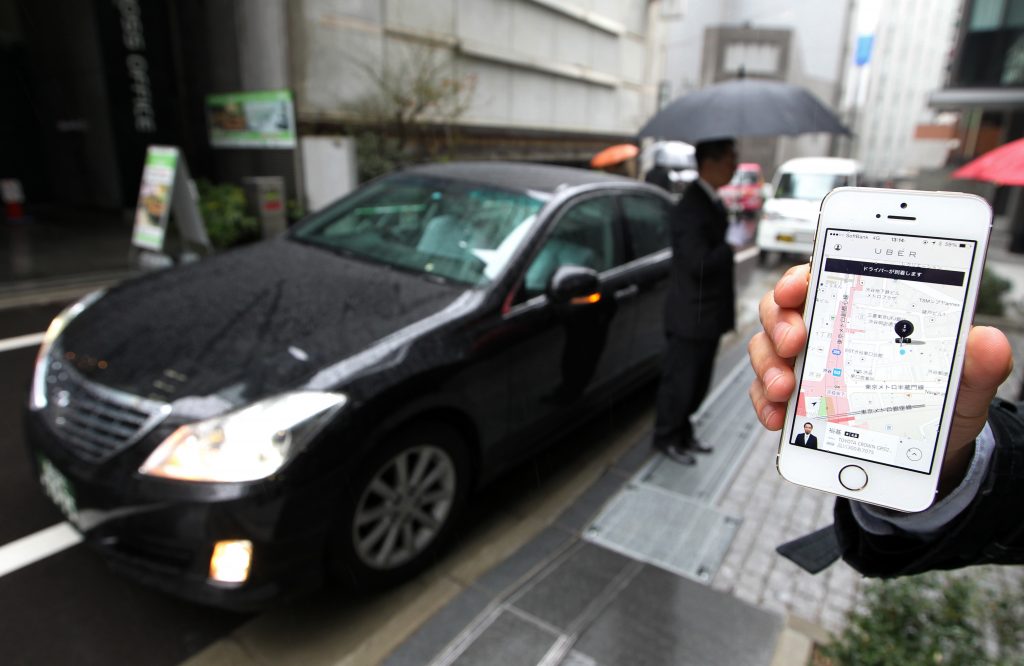 An Uber Japan Co. employee holds an Apple Inc. iPhone 5s showing a map on the Uber application for a photograph during a demonstration in Tokyo, Japan, on Wednesday, March 5, 2014. Uber Technologies Inc., the booking-app developer backed by Google Inc.s investment arm and Amazon.com Inc. founder Jeff Bezos, expanded to Tokyo using licensed taxi operators rather than private drivers. Photographer: Junko Kimura-Matsumoto/Bloomberg