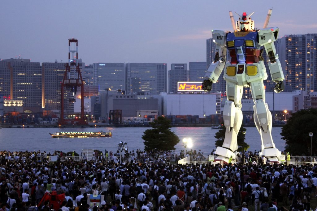 In this photo taken on July 11, 2009, people crowd to see 18-meter (60-foot) tall Gundam at a park in the manmade Odaiba island in Tokyo, Japan. If anything can encourage busy Tokyoites to take notice of their city's bid to host the 2016 Olympics, it's a replica of the popular robot animation Mobile Suit Gundam, the Japanese anime series robot, big enough to take on Godzilla. AP Photo/Koji Sasahara)